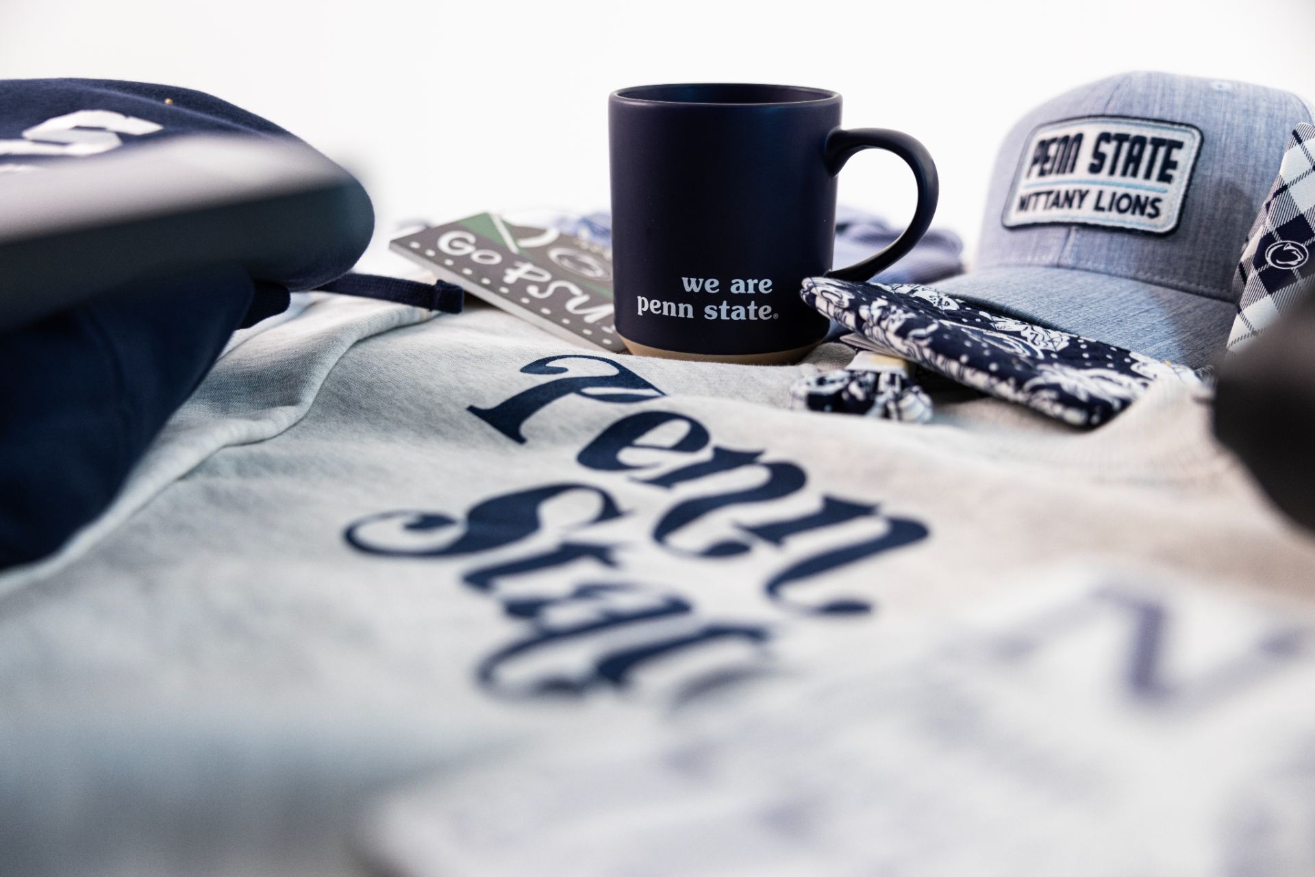 Assorted Penn State merchandise, including a t-shirt, a mug, a hat, and stickers